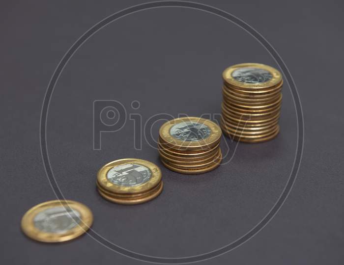 Stacks Of Golden And Silver Coins (1 Real) As In A Growing Graph, Representing Rise Or Fall On Black Bacground. Economy Concept. Copy Space. Selective Focus. Brazilian Coins