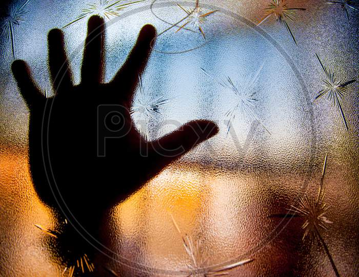 Silhouette Of Human Hand Against Window Glass