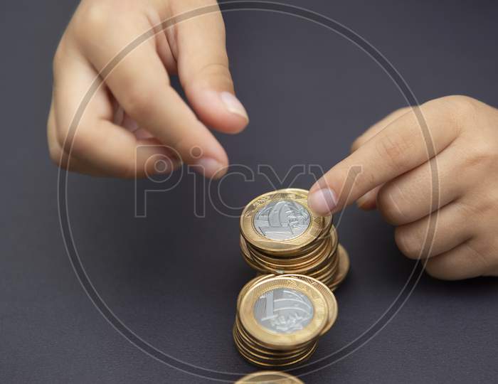 Child Hands Putting Golden And Silver Coin On Pile Of Coins. Concept Of Saving And Spending Money. Future Investment. Long-Term Economic Planning. Selective Focus. Copy Space.