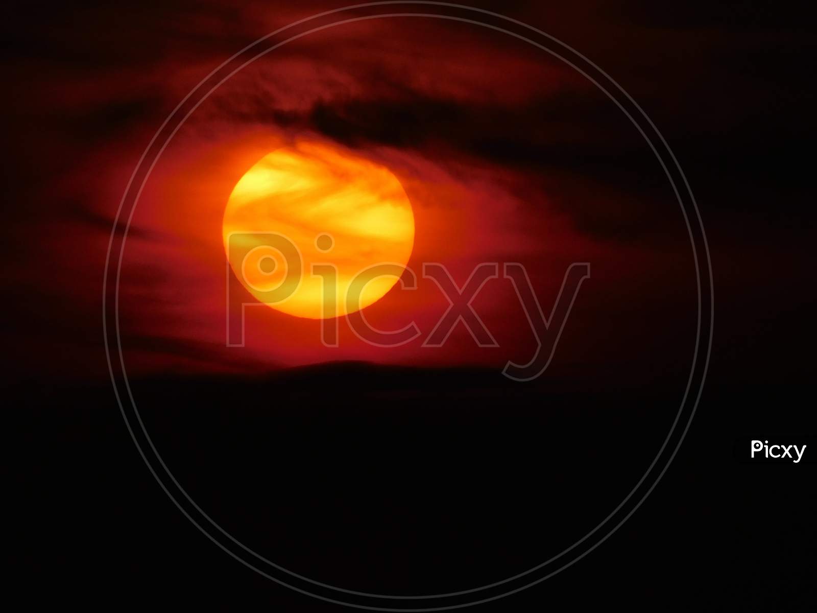 A view of the beautiful orange sun seen through the dark clouds