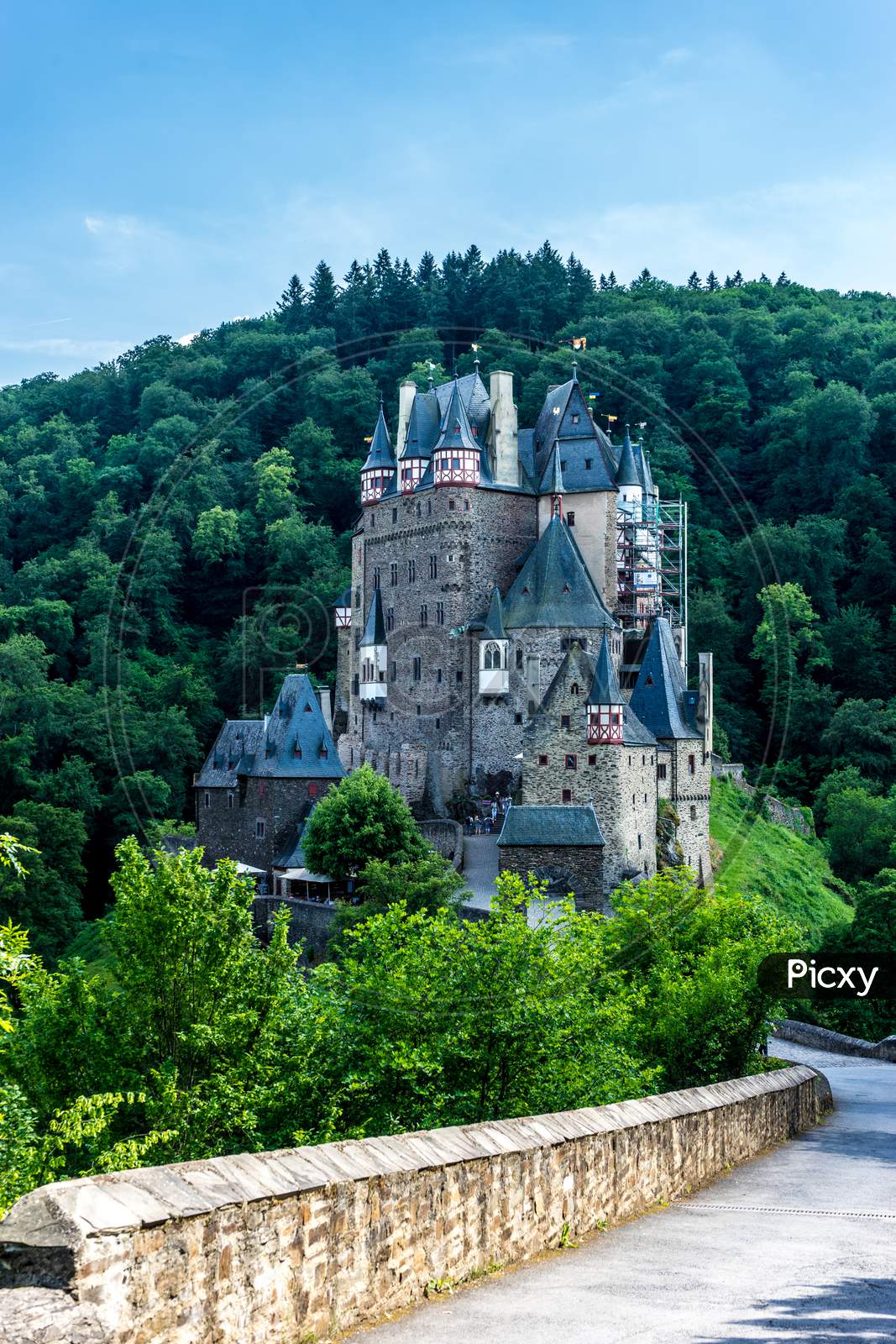 Germany, Burg Eltz Castle, Eltz Castle, A Castle With A Clock At The Top Of A Hill With Eltz Castle In The Background