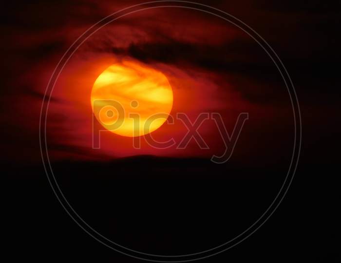 A view of the beautiful orange sun seen through the dark clouds