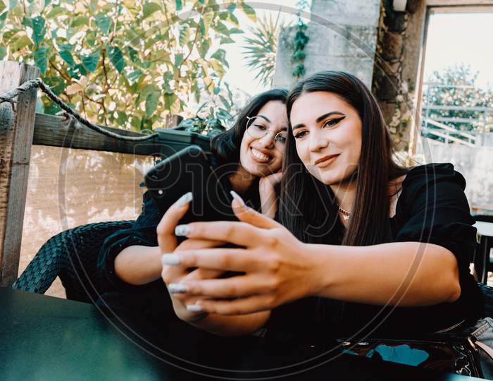 Couple Of Young Women Taking A Selfie In A Bar While Smiling