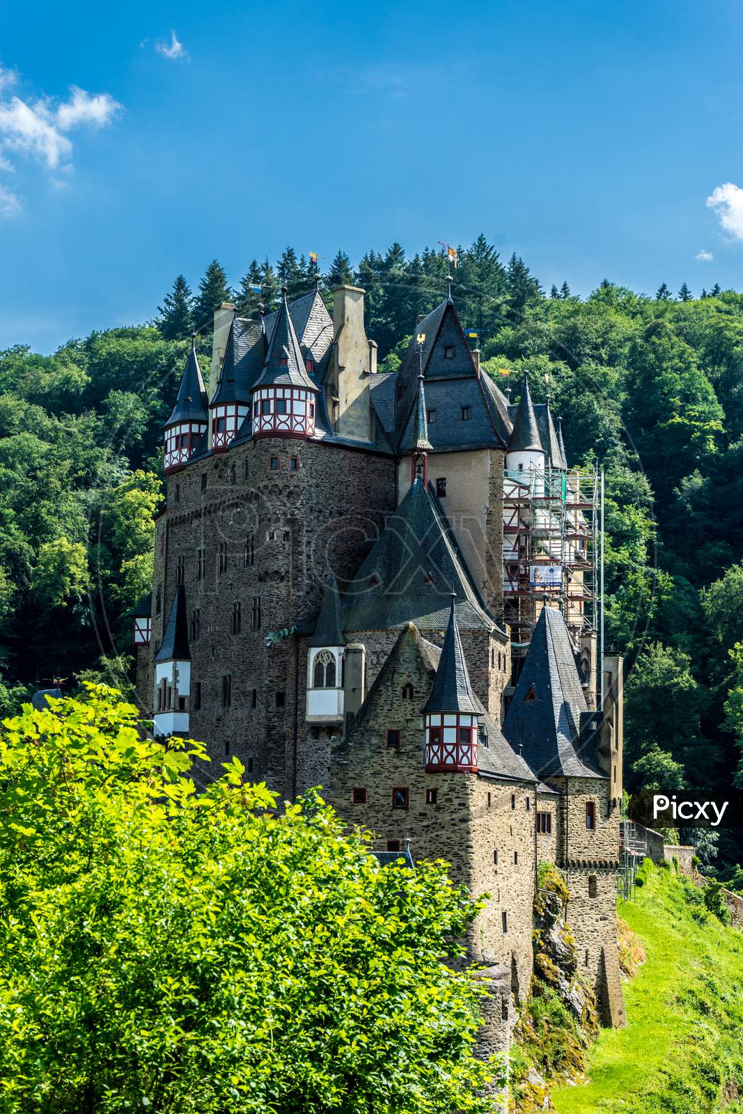 Germany, Burg Eltz Castle, A Castle With A Clock In The Middle Of A Forest
