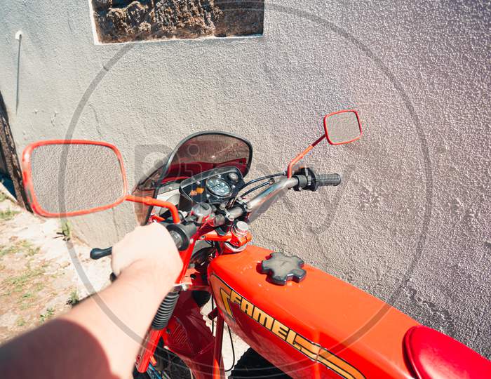 Point Of View Image Of A Man Holding A Vintage Red Motorbike During A Sunny Day