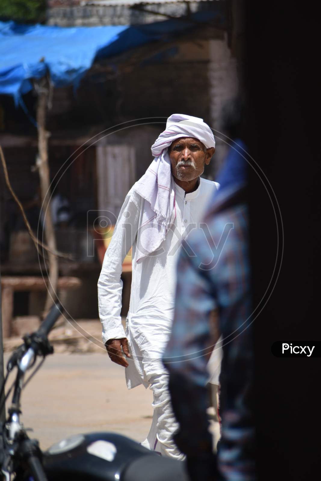 An indian old man walking on street of a town market.
