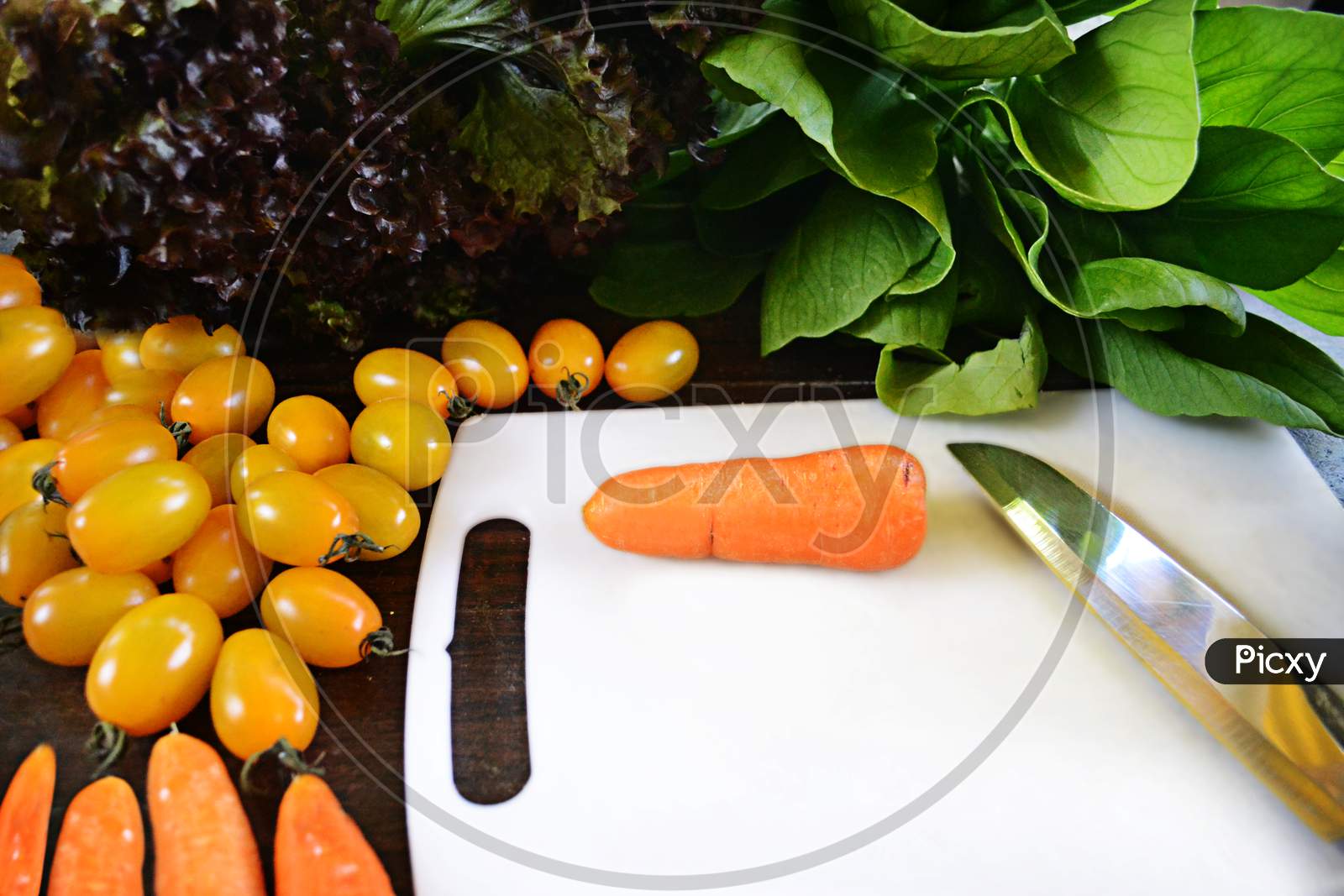 Organic Vegetables Ingredients Around White Cutting Board With Carrot And Knife