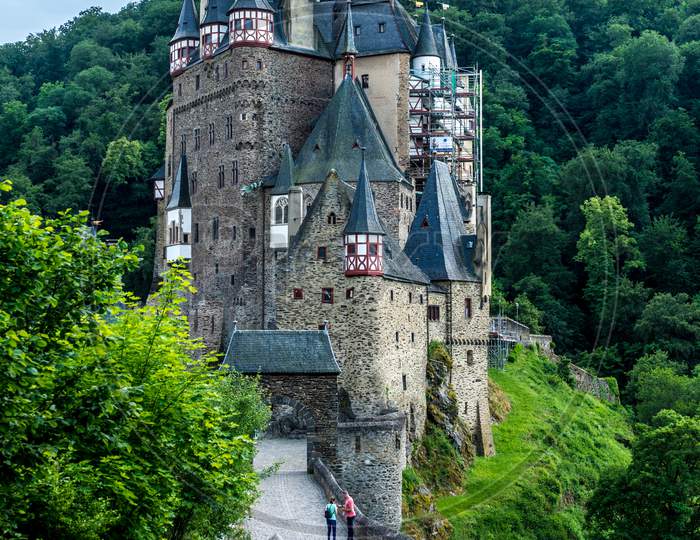 Germany, Burg Eltz Castle, Eltz Castle, A Stone Castle Next To A Forest With Eltz Castle In The Background