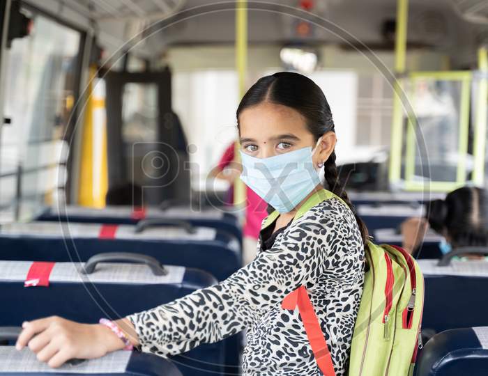 Portrait Of Girl Kid Student In Medical Mask Inside The School Bus Looking At Camera - Concept Of School Reopen Or Back To School With New Normal Lifestyle