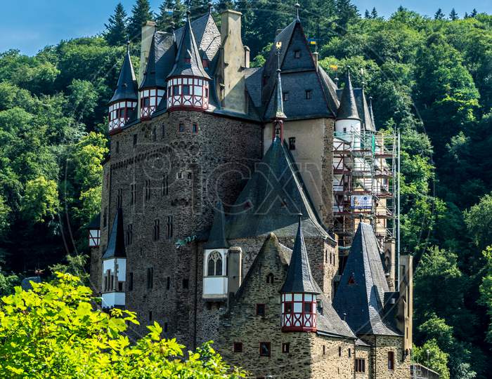 Germany, Burg Eltz Castle, A Castle With A Clock In The Middle Of A Forest