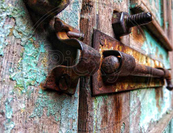 Old rusty nut bolt and iron door lock on a faded blue colored wooden door