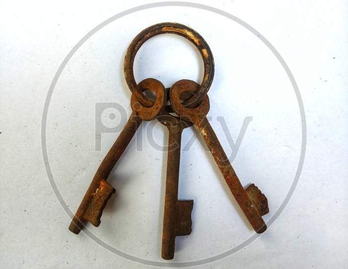 a bunch of old rusty iron keys in a ring on a white background