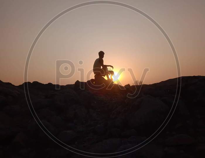 Man sitting on the horizon of hill sunset view
