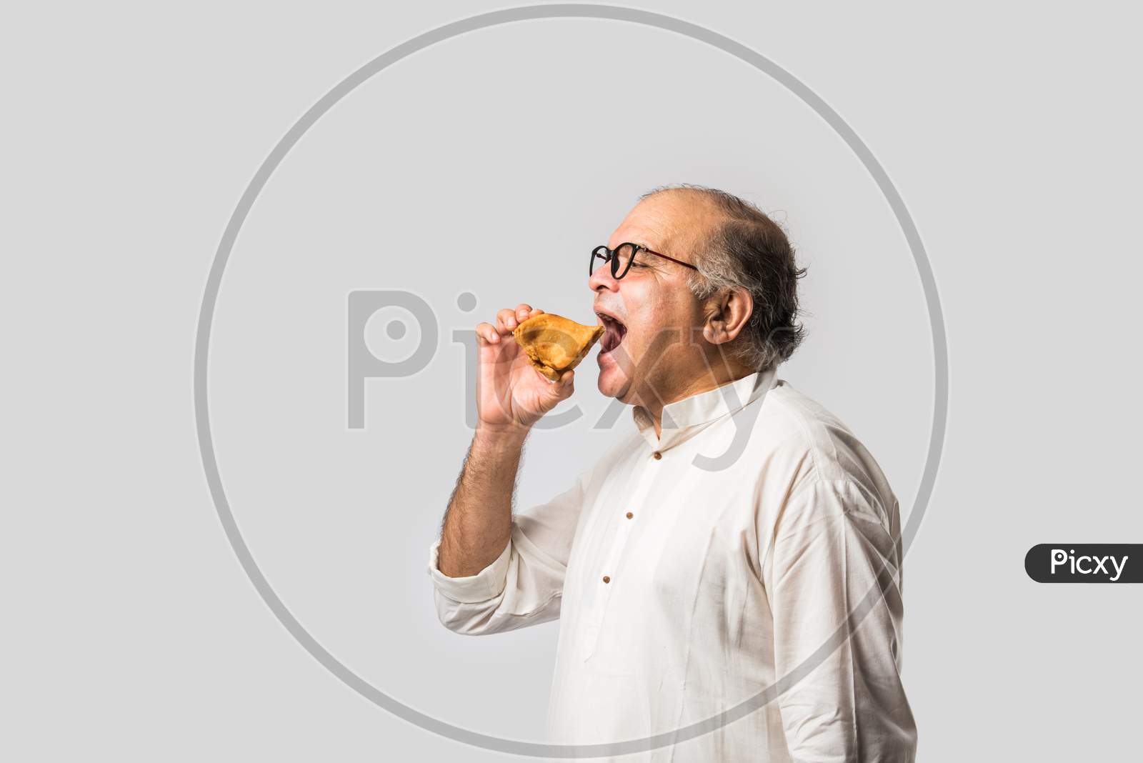 Indian Asian Senior Man Or Old Man Eating Samosa Snack