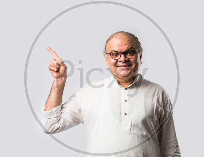 Portrait Of Cheerful Indian Senior Old Man Pointing Or Presenting Or In Hands Folded Pose