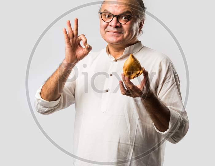 Indian Asian Senior Man Or Old Man Eating Samosa Snack