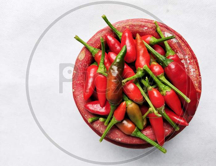 Red Chilli In A Red Colored Crock (Mud Made Pot) In A White Background