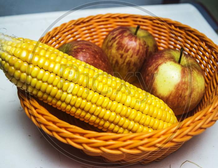 Raw Sweet Corn And Apple Arrange In A Plastic Wired Bascket