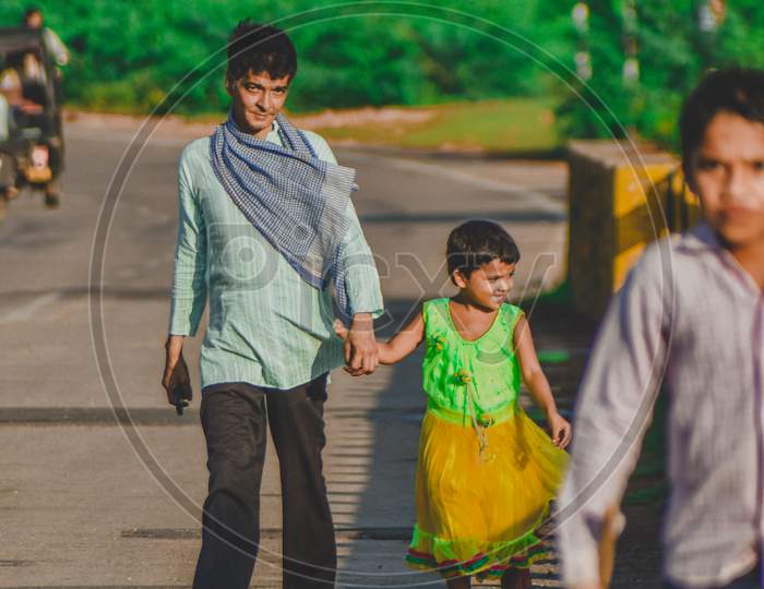 An indian father walking with his daughter on a road