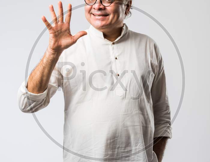 Portrait Of Cheerful Indian Senior Old Man Pointing Or Presenting Or In Hands Folded Pose