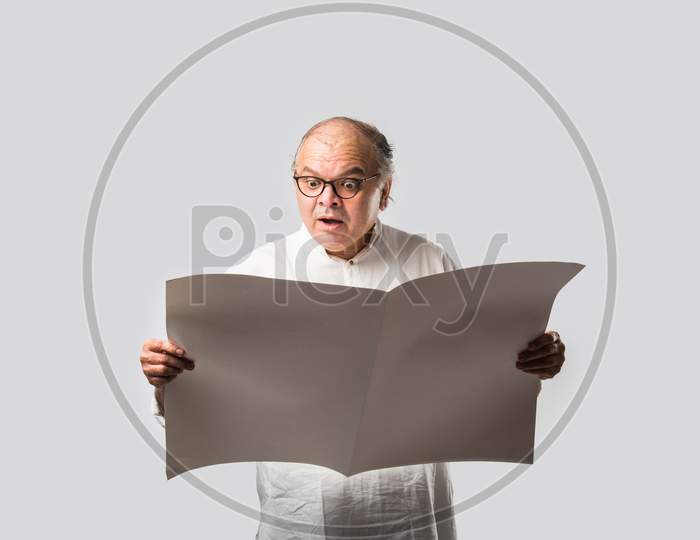 Indian Retired Senior Or Old Man Reading Book Or Newspaper
