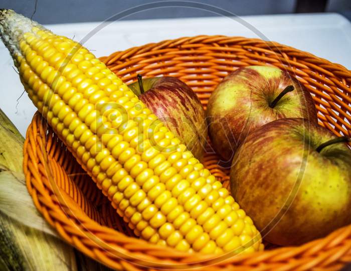 Raw Sweet Corn And Apple Arrange In A Plastic Wired Bascket