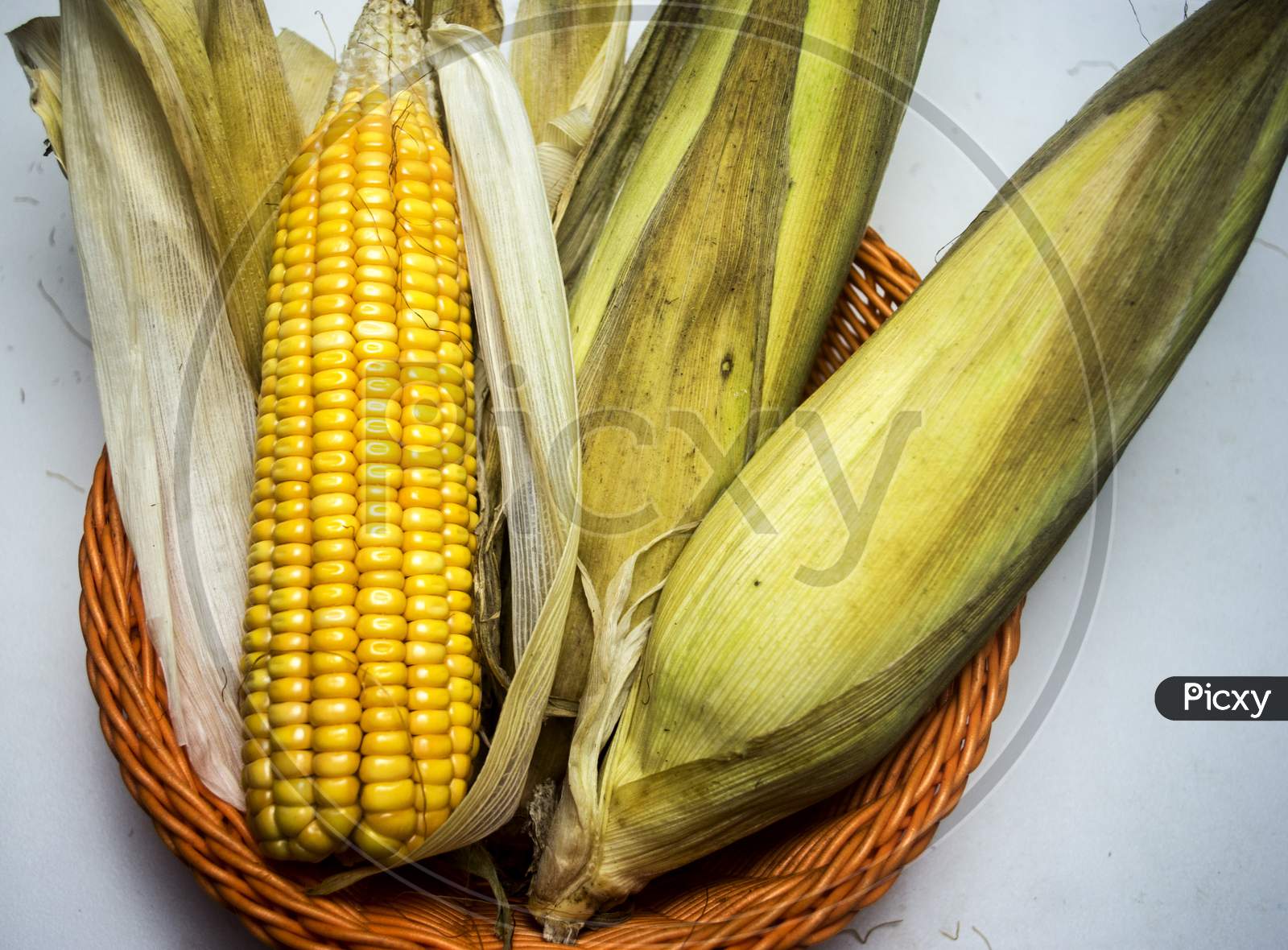 Raw Sweet Corn On Blurred Background With Dried Leaves