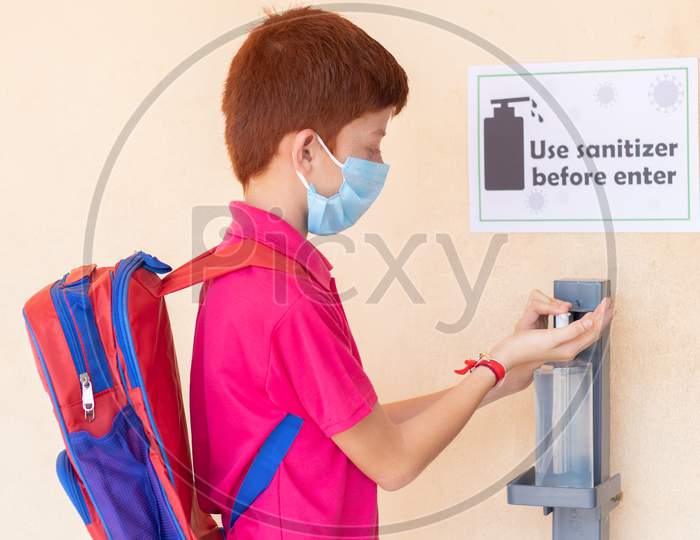 Kid With Medical Mask Using Hand Sanitizer Before Entering Classroom - Concept Of Back To School Or School Reopen And Coronavirus Or Covid-19 Safety Measures.