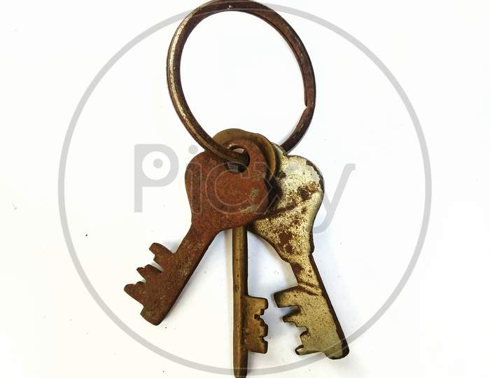 a bunch of old rusty iron keys in a ring on a white background