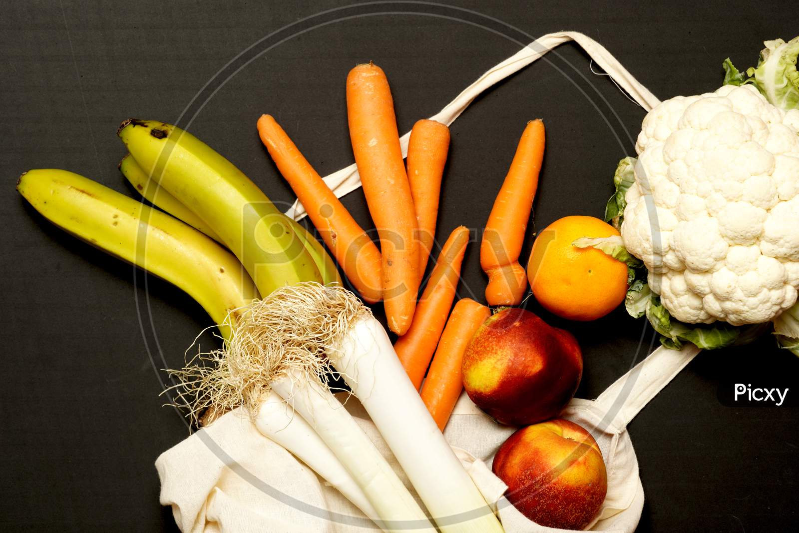 Top View Of Fruits And Vegetables Spilling Out Of A Cloth Shopping Bag. Zero Waste Concept. Flat Lay