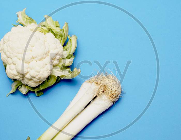 Top View Of Cauliflower And Leeks On Blue Background. Flat Lay . Vegetarian Or Vegan Concept