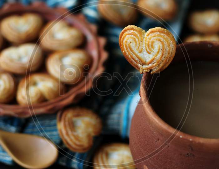 Earthen cup of tea with heart-shaped cookies