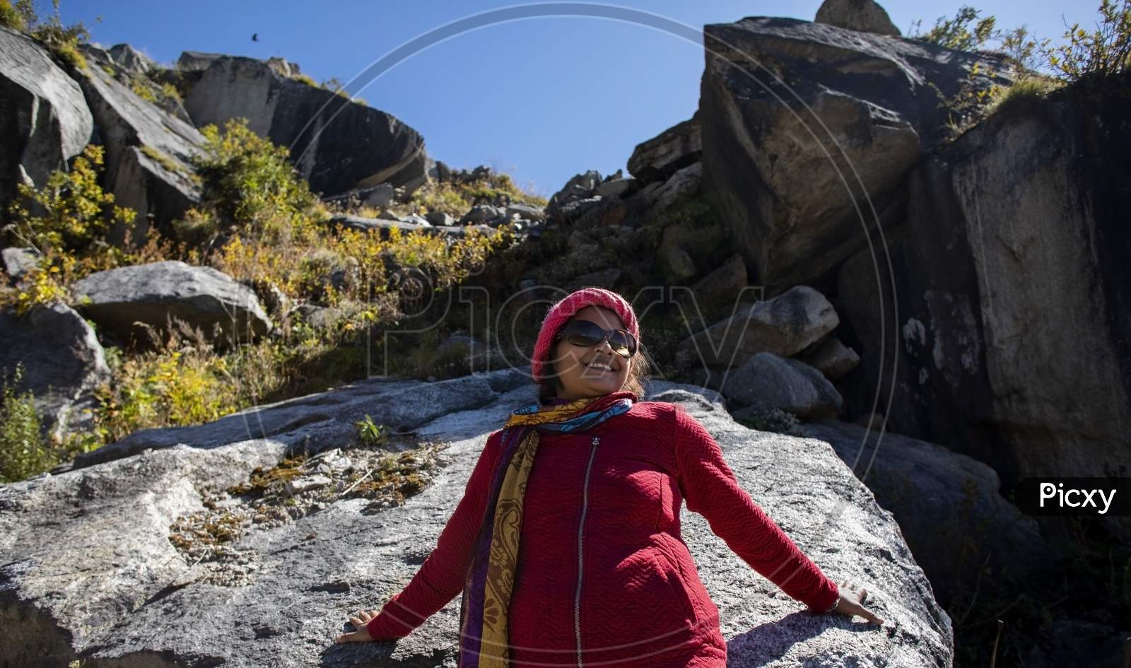 A Beautiful Young Lady With A Red Sweater And Sunglass Enjoying Nature On A Rock On The Mountain Himalayas