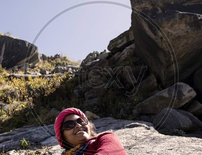 A Beautiful Young Lady With A Red Sweater And Sunglass Enjoying Nature On A Rock On The Mountain Himalayas