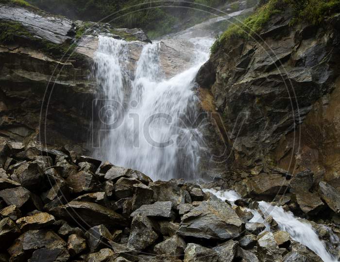 A Water Falls From A High Cliff In A Rocky Forest In Sikkim In India