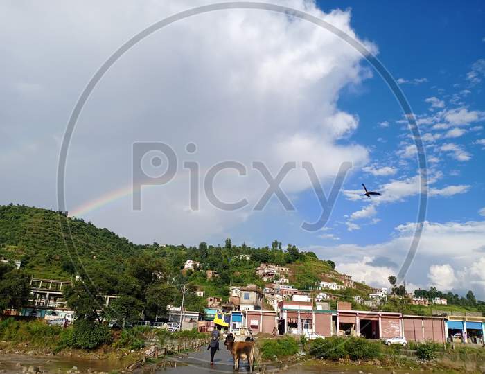 A rainbow appears on the landscape amidst scattered clouds after brief showers in Mendhar of Poonch district in Jammu and Kashmir