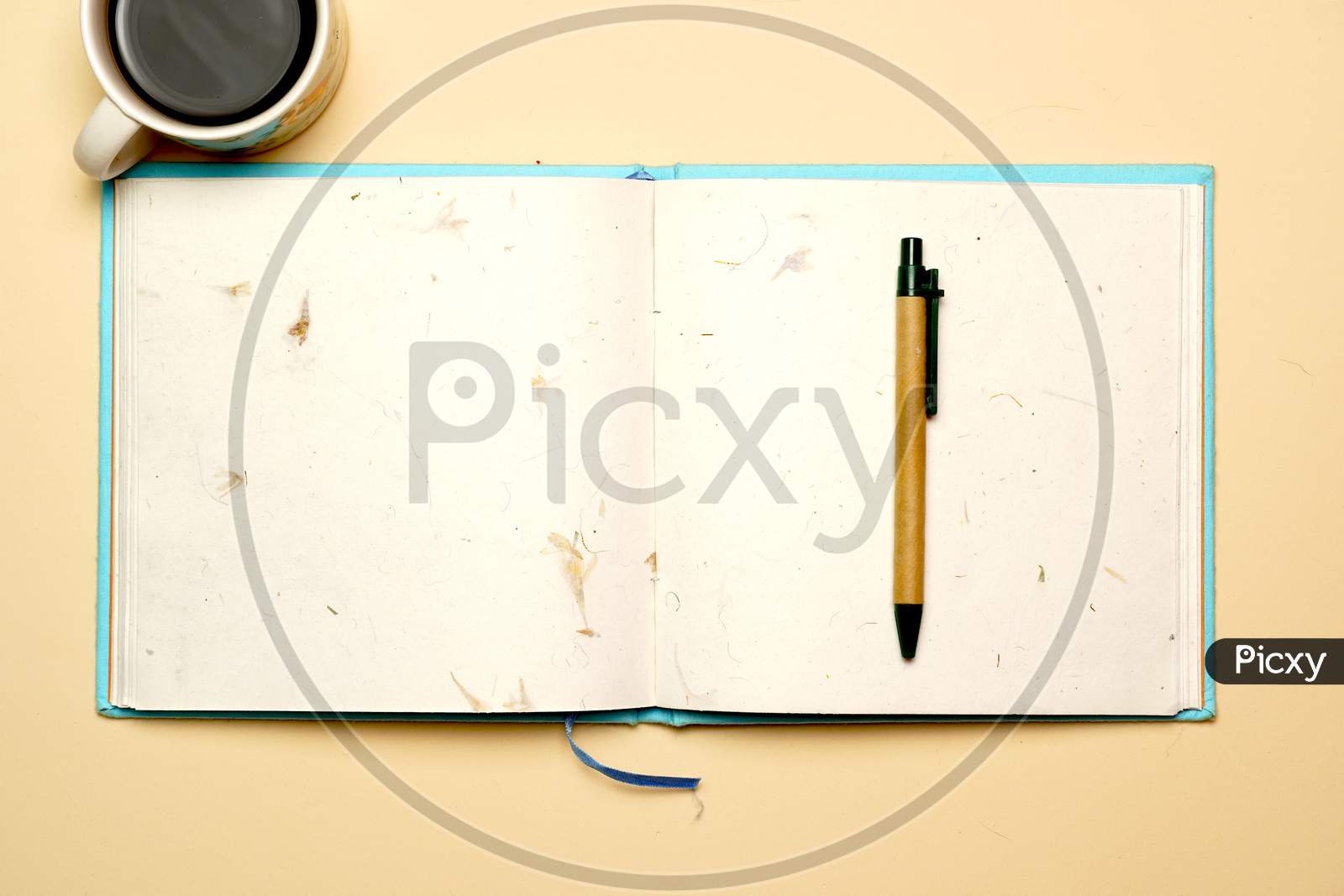 Top View Of Workspace With Coffee Reclined Paper Notebook And Pen On Flat Color Background. Flat Lay