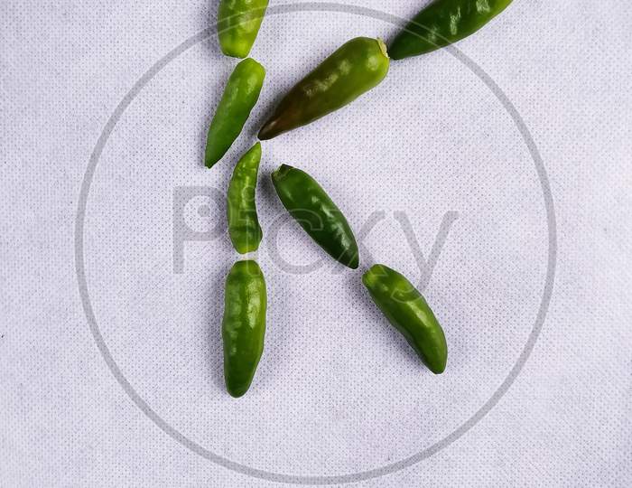 Red And Green Chilli In A "K" Shape In A White Background