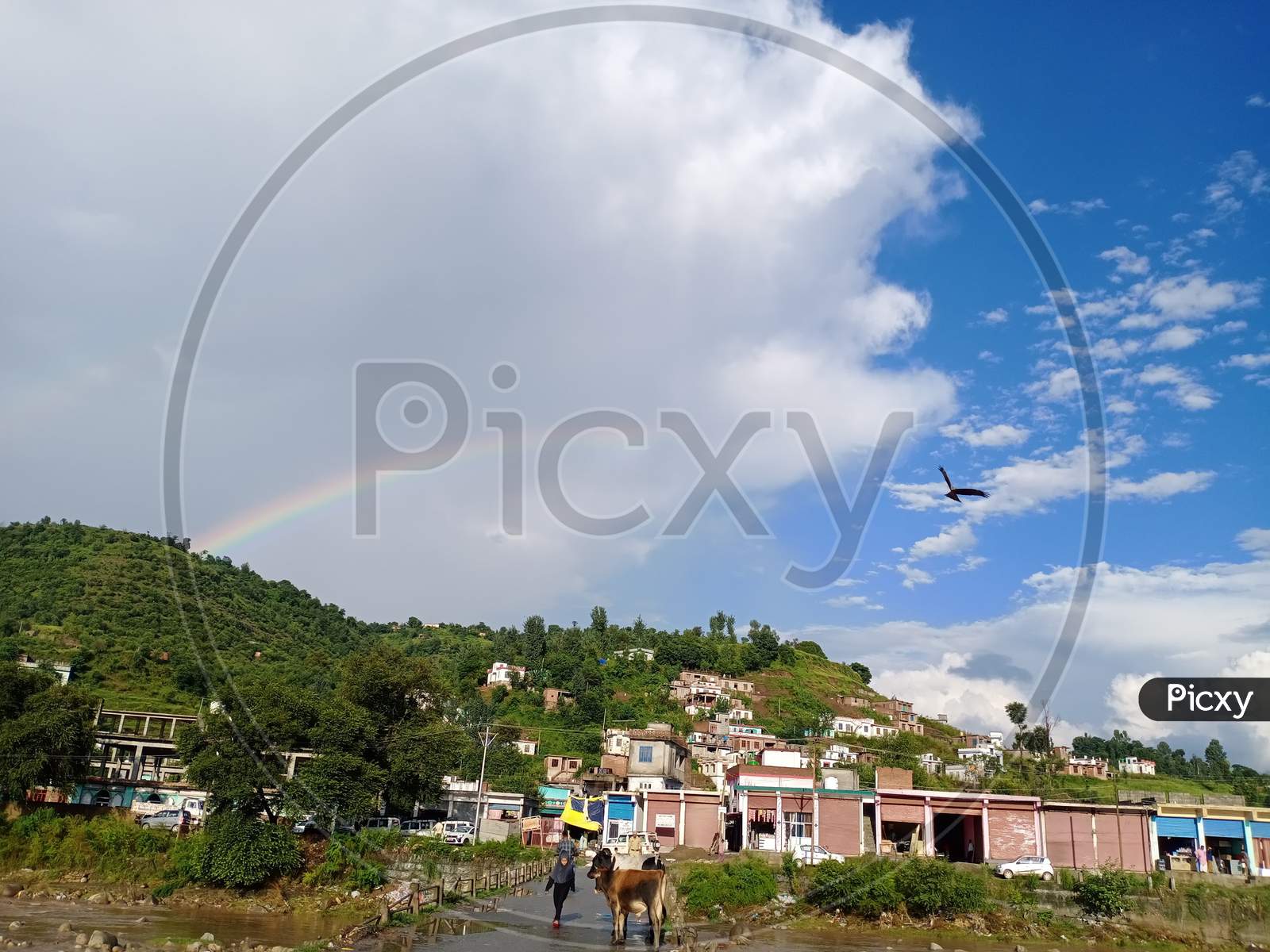 A rainbow appears on the landscape amidst scattered clouds after brief showers in Mendhar of Poonch district in Jammu and Kashmir