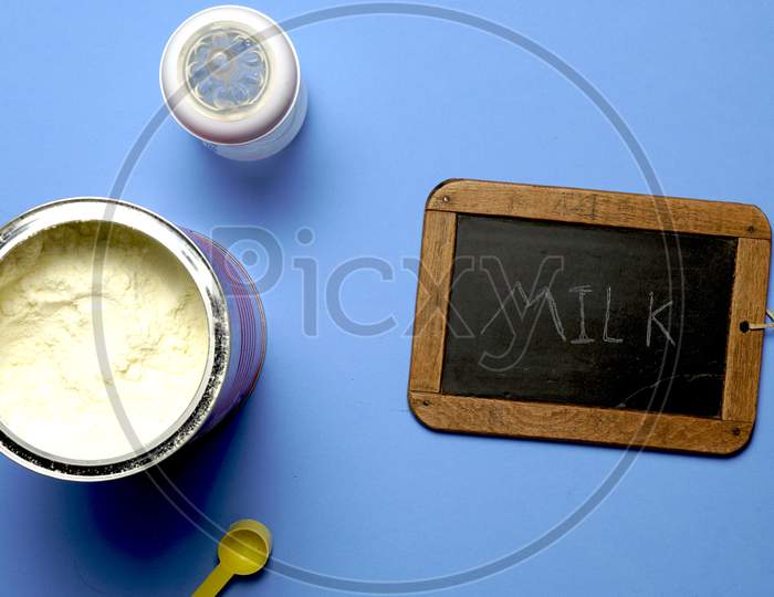 Top View Of Powdered Milk Next To A Blackboard With The Word Milk Written In Chalk- Flat Lay Flat Design