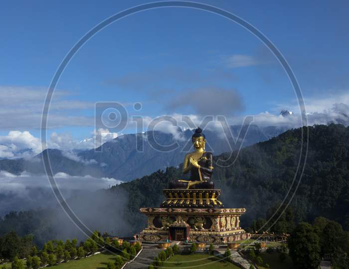 A Huge Statue Of Lord Buddha In A Sunny Morning In Buddha Park With The Kanchenjunga Snow Peak In Background In Sikkim In India