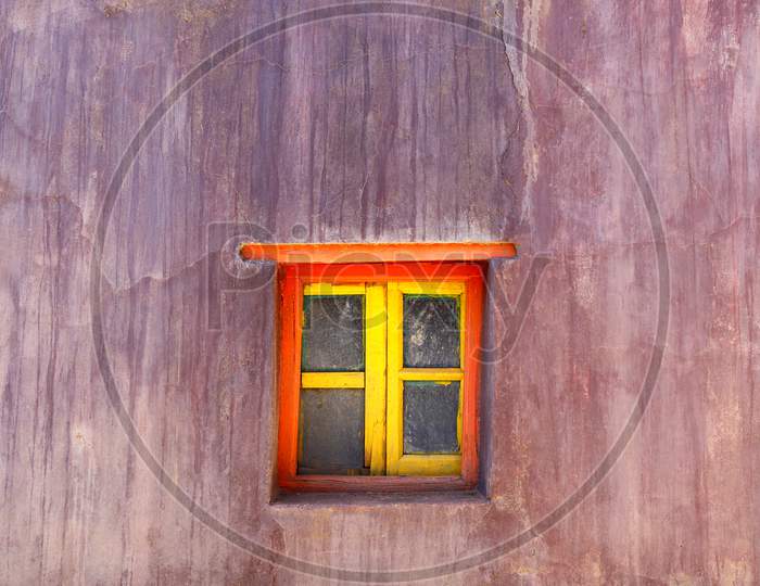 Red And Yellow Window On A Mud Wall