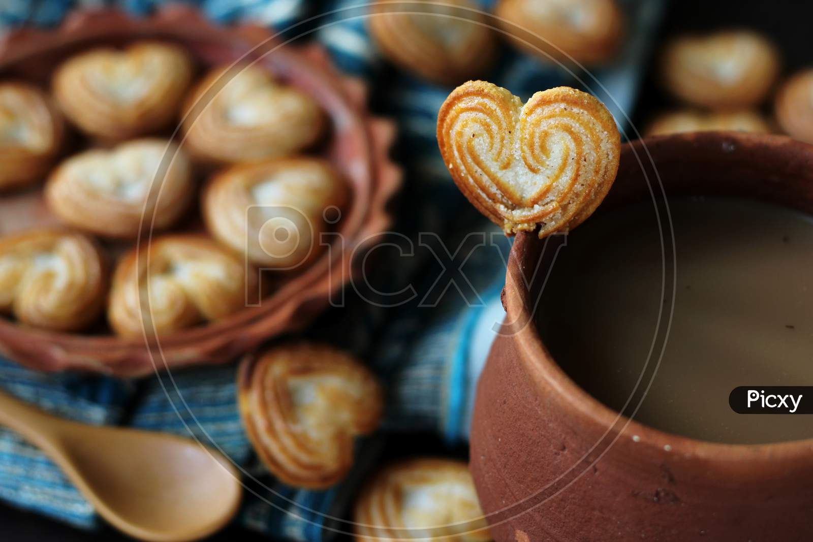 Earthen cup of tea with heart-shaped cookies