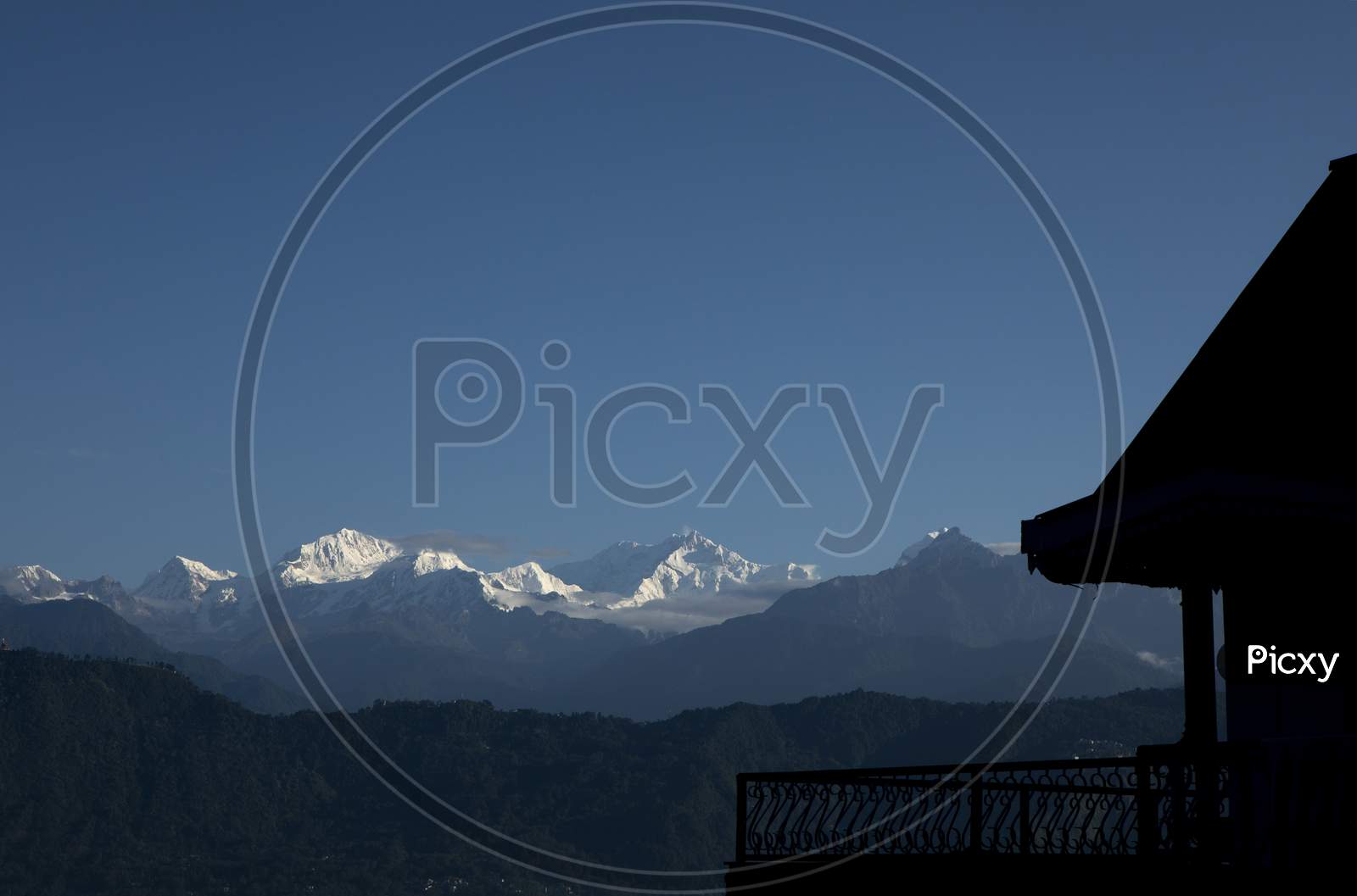 The Mighty Kanchanjunga With Other Snow Peaks At The Background Of A Small Village On The Slope Of Mountains On The Himalaya From The Balcony Of A Tourist Cottage In Sikkim