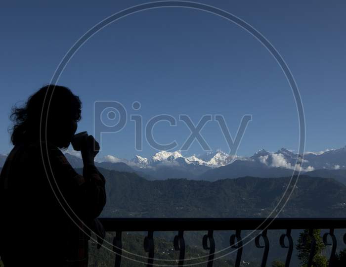 The Mighty Kanchanjunga With Other Snow Peaks At The Background Of A Small Village On The Slope Of Mountains On The Himalaya From The Balcony Of A Tourist Cottage With Morning Tea In Sikkim