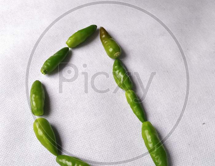 Green Chilli Making a "D" Shape In A White Background