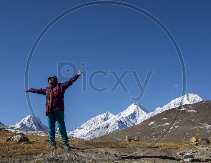 A Young Lady With Red Jacket On The Top Of Kunzum Pass In Front Of Snow Peaks On The Himalays In India