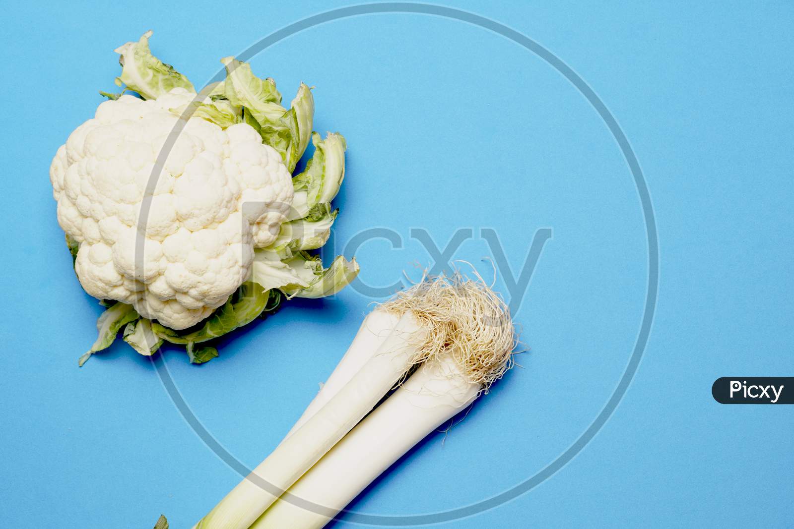 Top View Of Cauliflower And Leeks On Blue Background. Flat Lay . Vegetarian Or Vegan Concept
