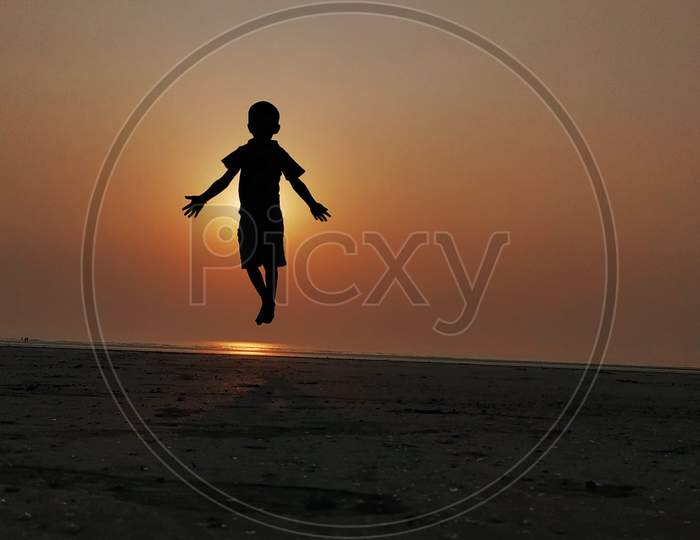 boy jumping in beach with beautiful evening