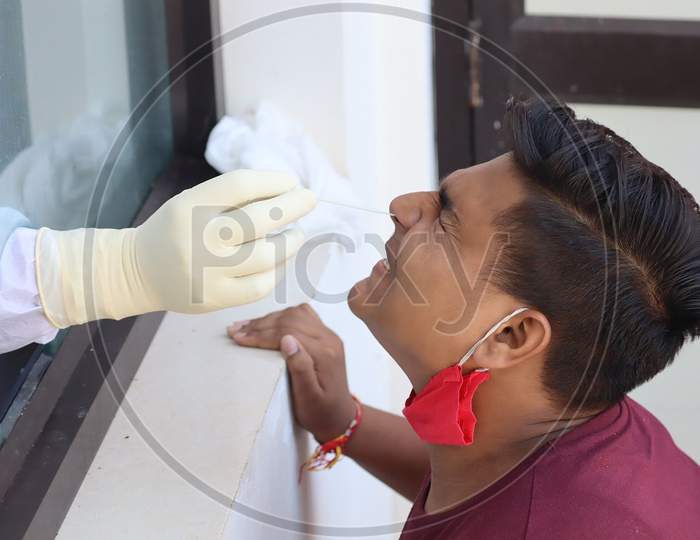 Healthcare workers wearing a Personal Protective Equipment(PPE) kit take nasal swab samples from person during corona virus antigen testing at Poonch